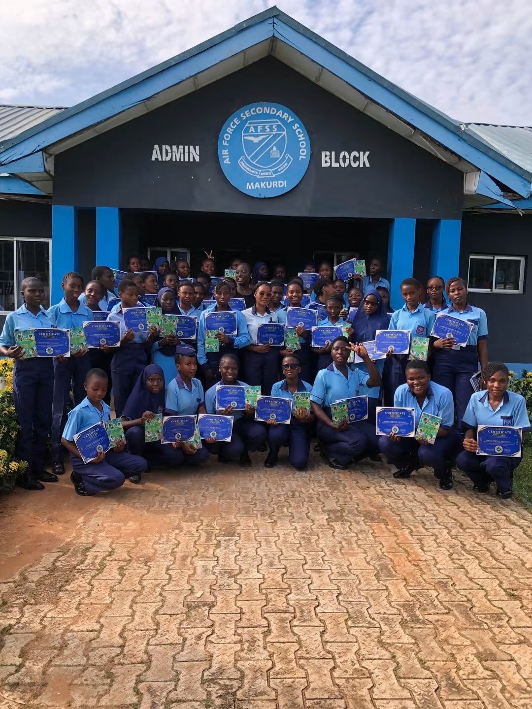 SheLearns AI workshop graduates proudly holding their certificates and guidebooks